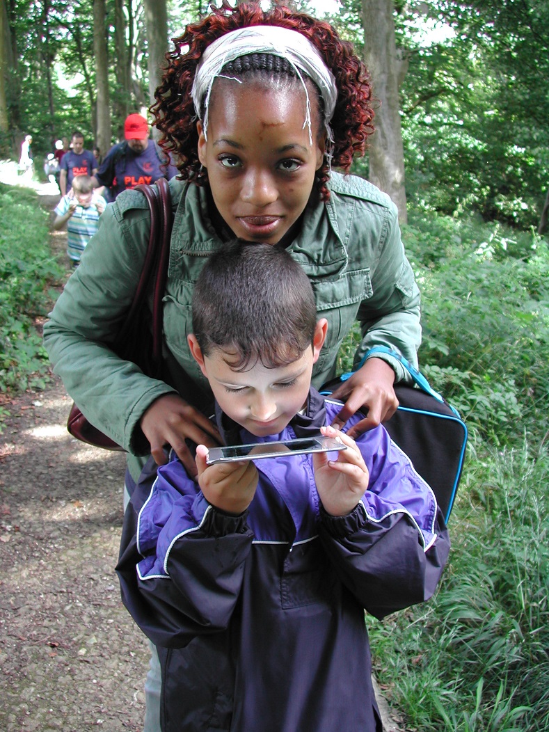 Sensory trail - children from a youth group use a mirror to view the tree tops above them 