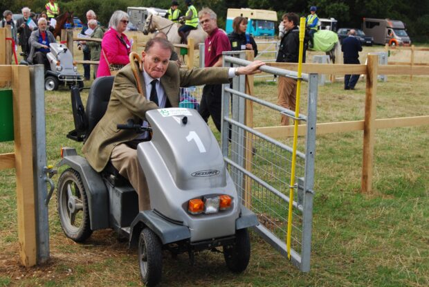 Lord Blencathra passes through gate on on his mobility vehicle