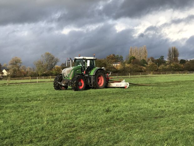 A tractor ploughing a green field