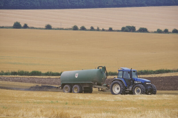 A tractor in a field dragging a trailer