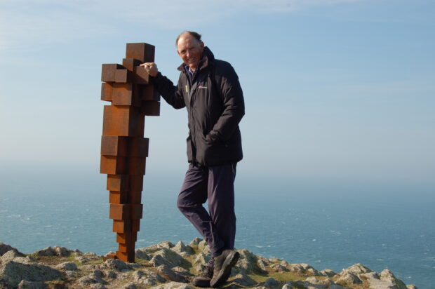 Andrew Sells with Antony Gormley statue on Lundy with the sea in the background