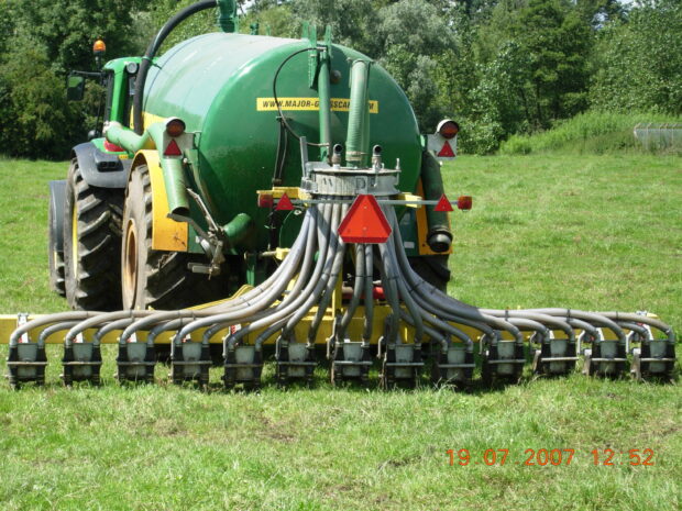 a tractor dragging a slurry injector in a field