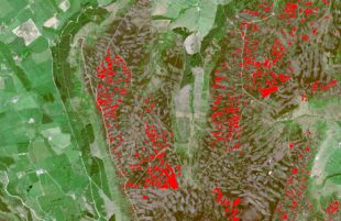 An aerial satellite image of a landscape is seen. Fields are patchworked together and small red sections highlight moorland areas.