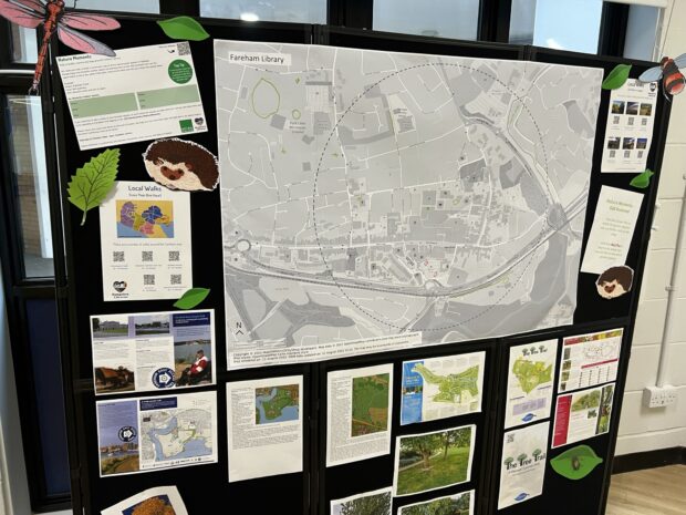 Photo shows a library pin board depicting lots of information of nature in the local area, from one of the pilots in Hampshire. There are lots of colourful print outs, and a large map which takes up most of the board. 
