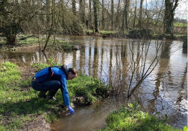 A Natural England adviser taking a water sample from a pond to monitor DNA