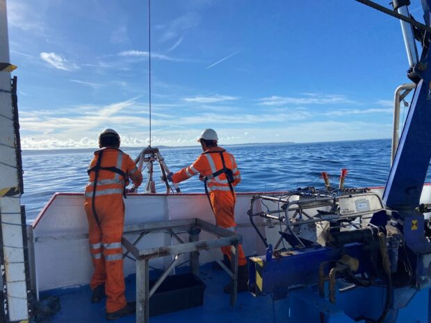 Two workers in high vis on a boat.