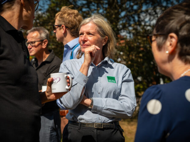 A woman mid conversation talking in a group outdoors.