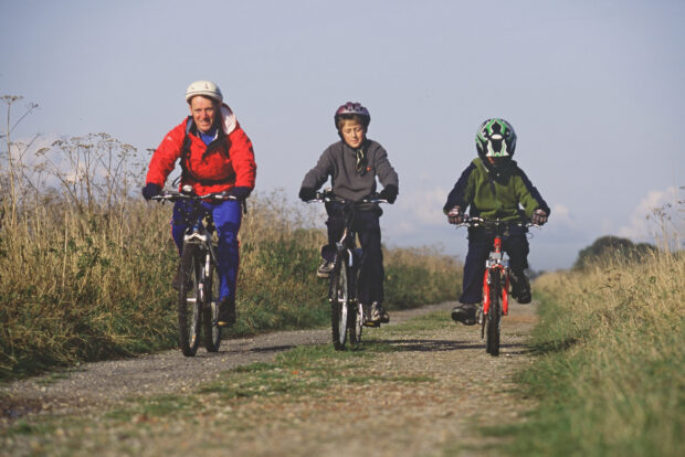 Family cycling along a coast path.